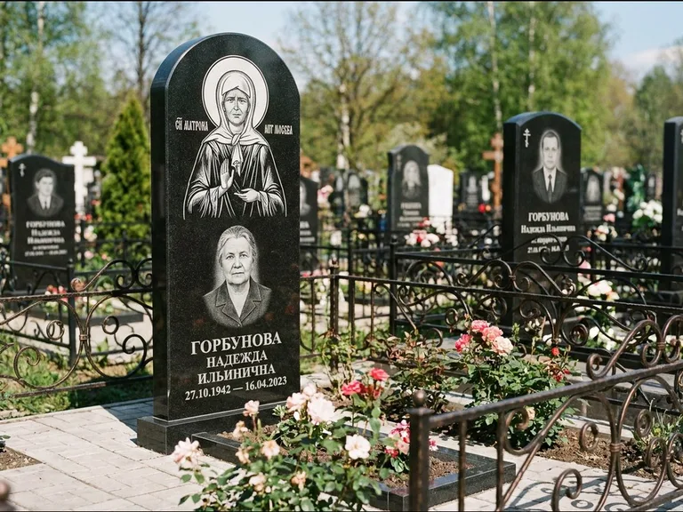 Памятник с гравировкой иконы: стела с арочным верхом и киотом под образ — гравировка образа Матроны Московской, гранитный цоколь с тёмной плиткой, работа «Ковалёв» в Набережных Челнах