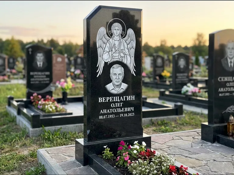 Памятник с гравировкой иконы: стела с резным навершием и нимбом в золоте — гравировка образа Спасителя, высокие разросшиеся туи полукругом, работа «Мельникова» в Набережных Челнах