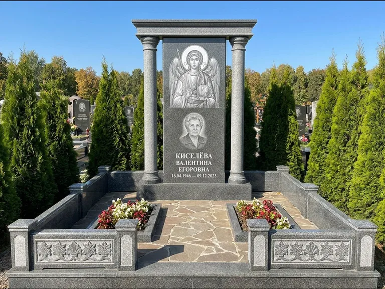 Памятник с гравировкой иконы: массивная стела с двускатным навершием-домиком — гравировка Николая Чудотворца, живая изгородь из туи, работа «Журавлёв» в Набережных Челнах