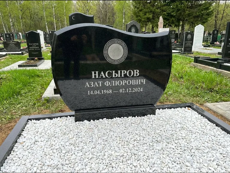 Мусульманский памятник: стела с волнообразным скошенным верхом — гравировка мечети под полумесяцем и звёздами, белая мраморная крошка с бордюром, работа «Насыров» в Набережных Челнах