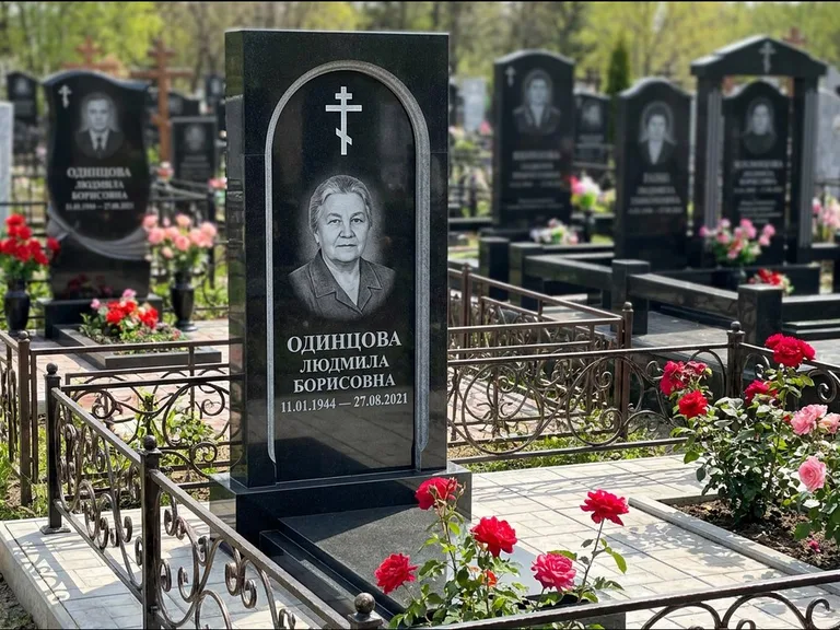 Памятник из чёрного гранита — скромная невысокая стела с крестом с терновым венцом, работа «Лаврентьева» в Набережных Челнах