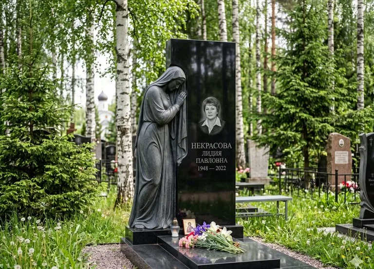 Гранитная фигура скорбящего мужчины у чёрной стелы в Набережных Челнах